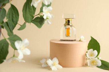 Bir şişe parfüm ve bej arka planda yasemin çiçekleri.