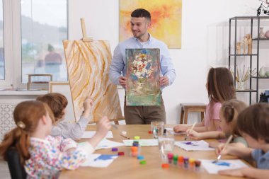 Çocuklara resim dersinde resim yapmayı öğreten bir adam.