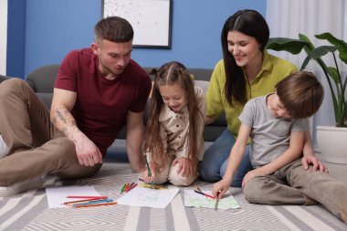 Ebeveynler çocuklarına evde yerde çizim yapmayı öğretiyor.