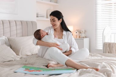 Yatma vakti. Anne, evde yatağında sevimli küçük bebeğiyle.