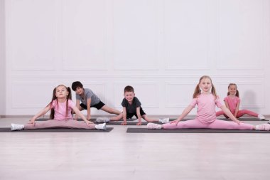 Sınıftaki minderler üzerinde yoga yapan bir grup çocuk.