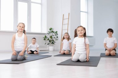 Sınıfta yoga minderleri üzerinde bir grup çocuk.