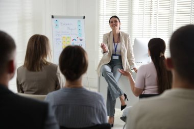 Kadın içeride seyirci önünde konuşma yapıyor.