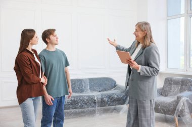 Tabletle gülümseyen emlakçı evde çiftlerle çalışıyor.