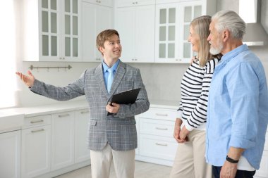 Mutfakta çiftlerle çalışan gülümseyen emlakçı.