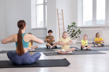 Sınıfta koçla yoga yapan bir grup çocuk.