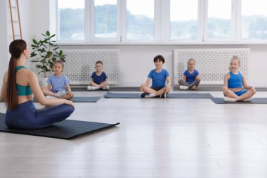 Sınıfta koçla yoga yapan bir grup çocuk.