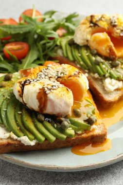 Avokadolu lezzetli sandviçler, haşlanmış yumurta, somon, domates ve roka, yakın plan.