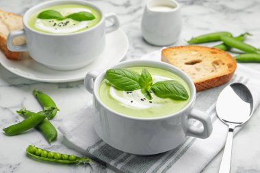 Fesleğenli bezelye kremalı çorba beyaz mermer masada servis edilir.