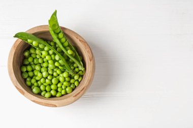 Beyaz ahşap masada taze taze taze bezelyeler, üst manzara. Metin için boşluk