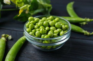 Taze taze bezelyeler siyah ahşap masada, yakın plan.