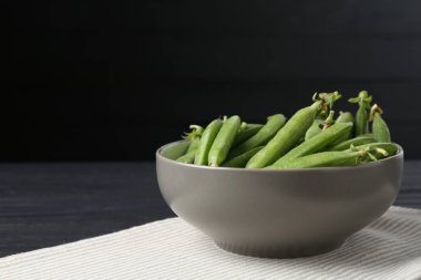 Siyah ahşap masada taze taze taze bezelyeler, yakın plan. Metin için boşluk