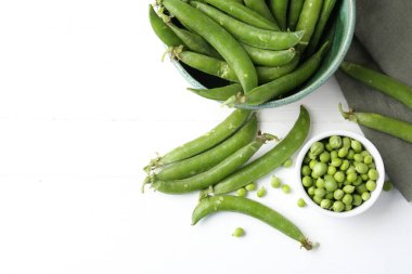 Taze taze bezelyeler beyaz ahşap masada, düz yerde. Metin için boşluk