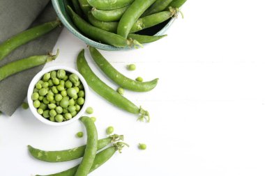 Taze taze bezelyeler beyaz ahşap masada, düz yerde. Metin için boşluk