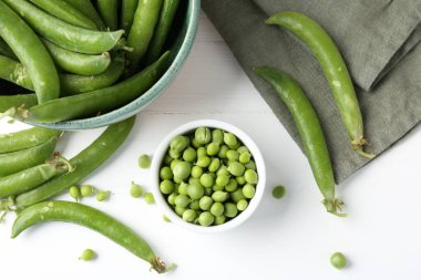 Taze taze bezelyeler beyaz ahşap masada, düz yatıyordu.