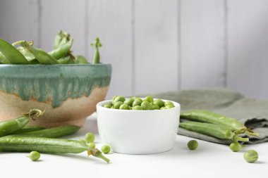 Taze taze bezelyeler beyaz ahşap masada, yakın plan.