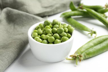 Taze taze bezelyeler beyaz ahşap masada, yakın plan.