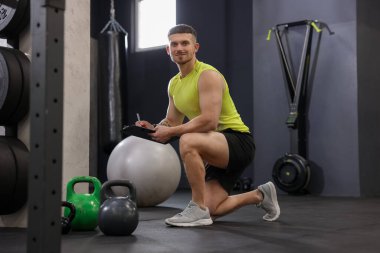 Spor salonunda klasörlü ve spor aletli kişisel antrenör.