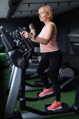 Son sınıf kadın spor salonunda eliptik makine eğitimi alıyor.