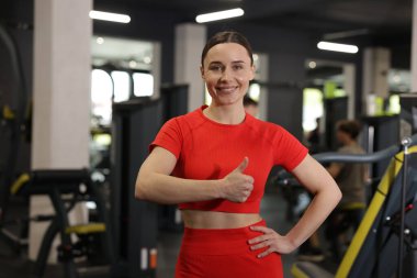 Spor salonunda baş parmağını gösteren kişisel antrenör.