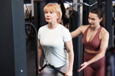 Spor salonunda profesyonel antrenör tarafından yönetilen son sınıf kadın makara makinesi eğitimi.