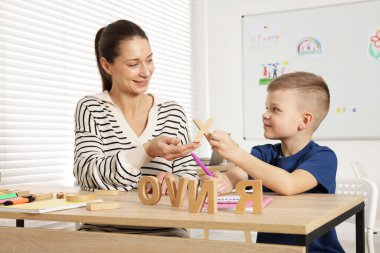 Okulda masa başında öğretmeniyle mektup öğrenen tatlı bir çocuk.