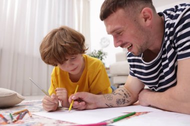 Baba oğluna evde yerde çizim yapmayı öğretiyor.