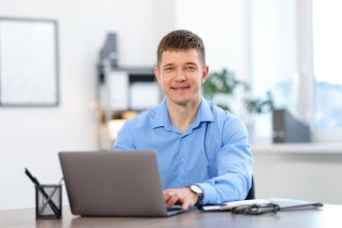 Ofiste masada dizüstü bilgisayarda çalışan adam