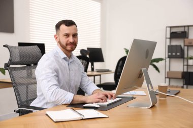 Ofisteki bilgisayarda çalışan adam.