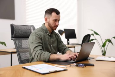 Ofiste masada dizüstü bilgisayarda çalışan adam