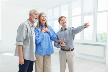 Gülümseyen emlakçı içeride çiftlere daire gösteriyor.