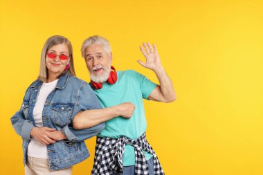 Turuncu arka planda şık giyinmiş son sınıf çifti, mesaj için yer var.