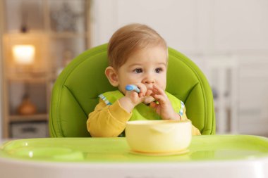 Küçük şirin bebek, yüksek sandalyede sağlıklı yiyecekler yiyor.