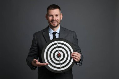 Hedef alınıyor. Dart tahtası ve gri arka planda oku olan bir adam.