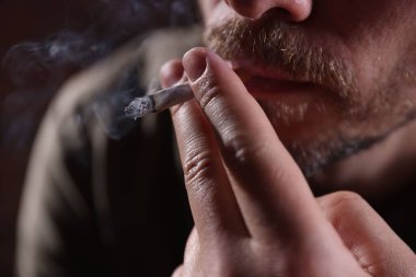 Arka planda sigara içen adam, yakın plan.