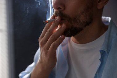Arka planda sigara içen adam, yakın plan.