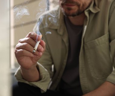 Arka planda sigara içen adam, yakın plan.