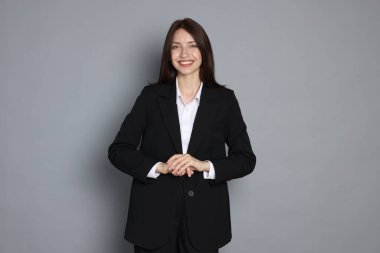 Gri arka planda takım elbiseli mutlu kadın