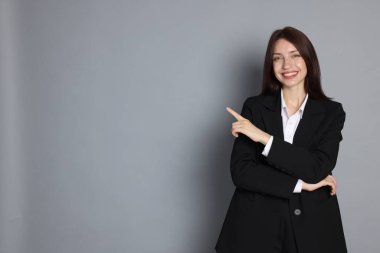 Gri arka planda takım elbiseli mutlu kadın, mesaj için boşluk