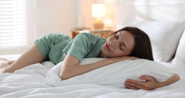 Evdeki yumuşak yatakla yatakta uyuyan bir kadın.