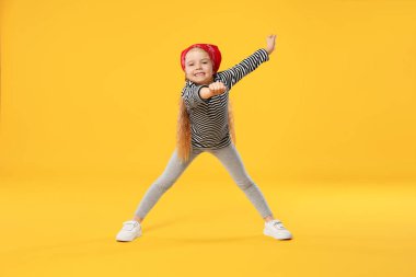 Turuncu arka planda dans eden tatlı küçük kız.