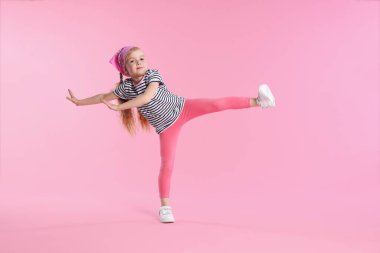 Pembe arka planda dans eden tatlı küçük kız.