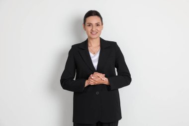 Hafif arka planda takım elbiseli kendine güvenen iş kadını.