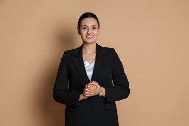 Bej arka planda takım elbiseli kendine güvenen bir iş kadını.