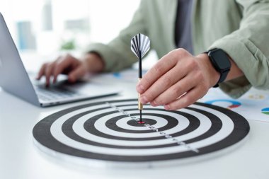 Dart oklu bir adam içeride çalışırken dart tahtasına nişan alıyor, yakın plan.