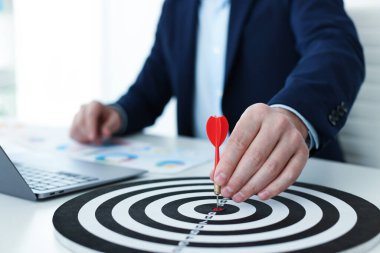 Dart oklu bir adam içeride çalışırken dart tahtasına nişan alıyor, yakın plan.