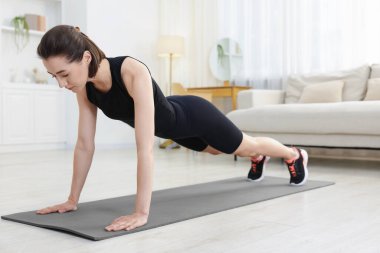 Evde tahta egzersizi yapan bir kadın. Spor ve sağlıklı yaşam tarzı