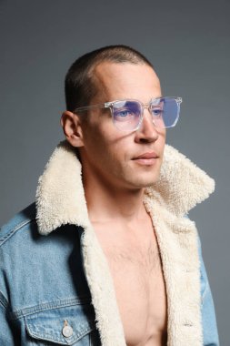 Gri arka planda şık giyinmiş yakışıklı bir adamın moda portresi.