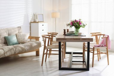 Odada güzel çiçekler ve bulaşık takımı olan yemek masası. İç tasarım