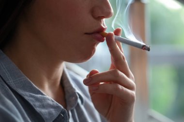 İçeride sigara içen bir kadın, yakın plan. Kötü alışkanlık.